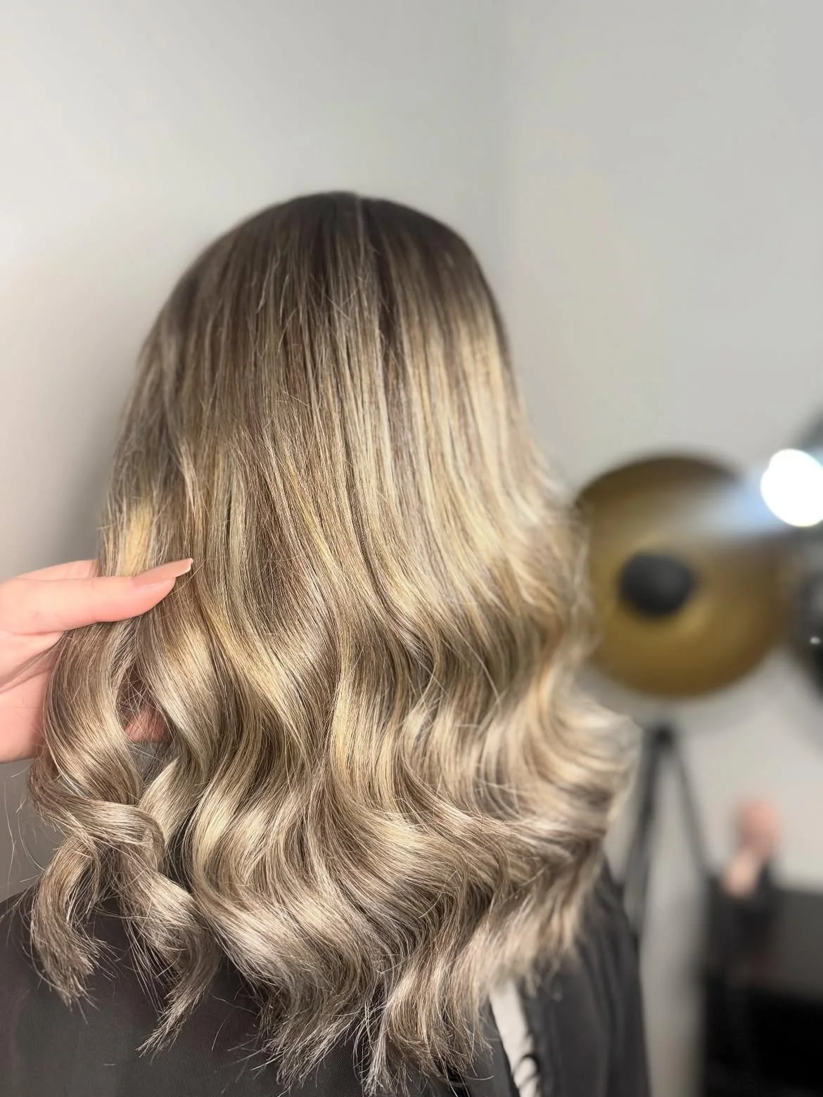 Balayage blond cendré sur cheveux mi-longs ondulés réalisé au salon LM Coiffure à Audenge