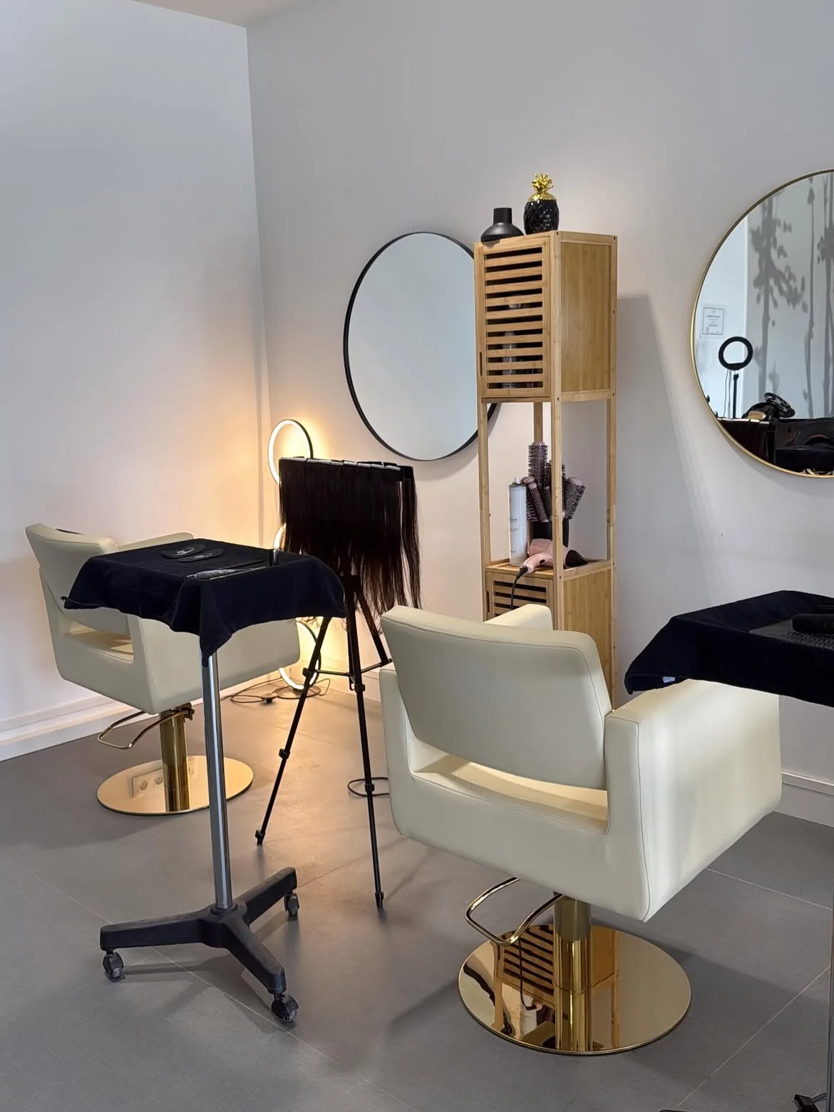 Poste de coiffage du salon LM Coiffure à Audenge : fauteuils blancs à pied doré, miroirs ronds et mobilier en bois clair